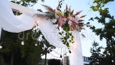 在阳光明媚的夏日，<strong>婚礼</strong>拱门装饰着鲜花。 节日花装饰。 玫瑰和<strong>羽毛</strong>草